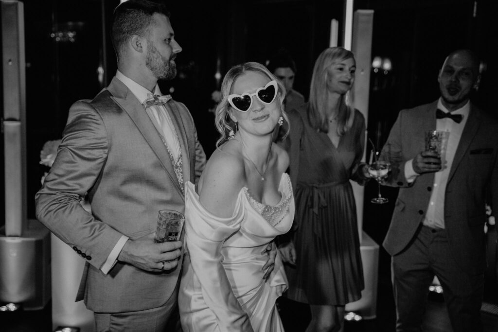 Braut beim Tanzen mit Sonnenbrille, der Bräutigam hinter ihr, Planung: Sophia von Aspern, Hochzeitsplanerin