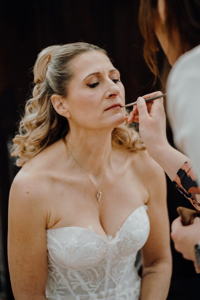 Braut bekommt den Lippenstift nachgezogen von Styliytin Caro Grüning, Planung: von Aspern Weddings