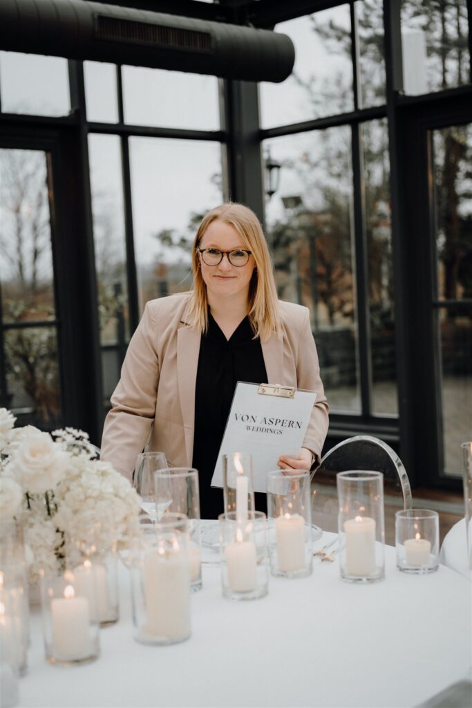 Hochzeitsplanerin Sophia von aspern steht mit Klemmbrett vor Tablesetting mit vielen Kerzen in Lüneburg