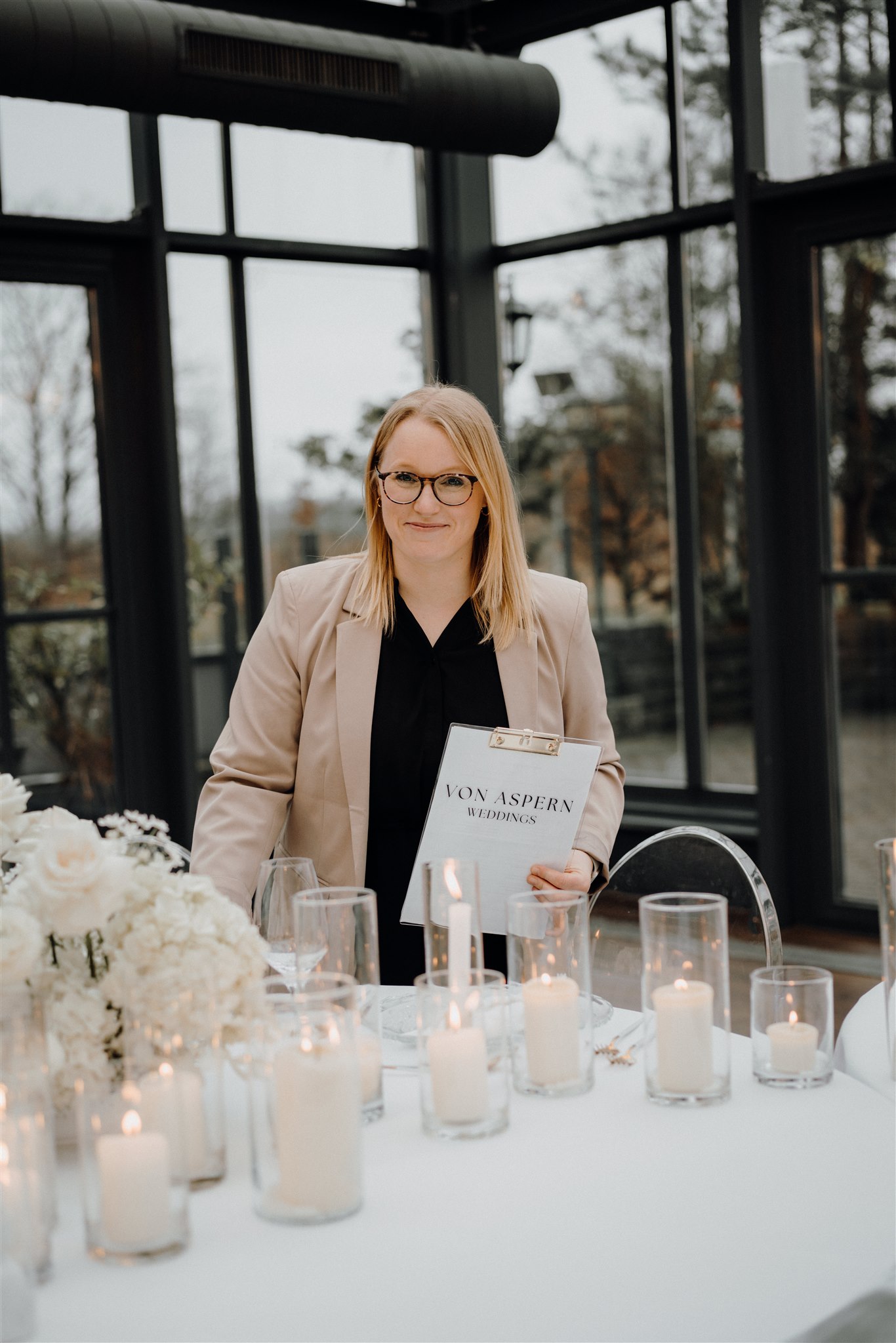 Hochzeitsplanerin Sophia von aspern steht mit Klemmbrett vor Tablesetting mit vielen Kerzen in Lüneburg