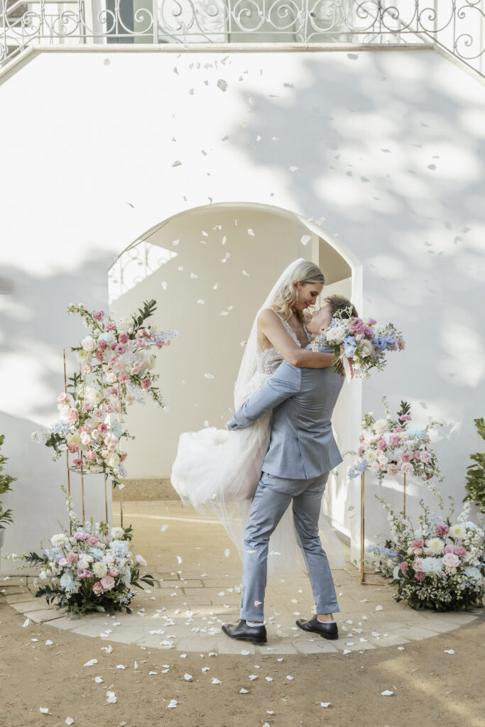 Bräutigam hebt Braut hoch im Blütenregen, Planung: Sophia von Aspern
