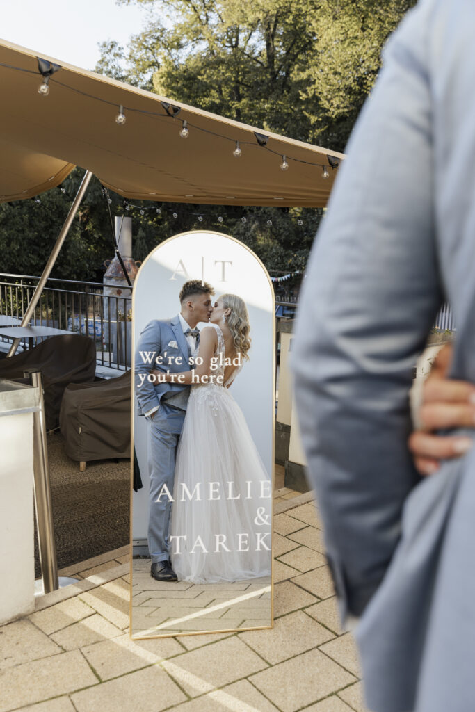 Hochzeitspaar küsst sich im Willkommensspiegel, Planung: Sophia von Aspern