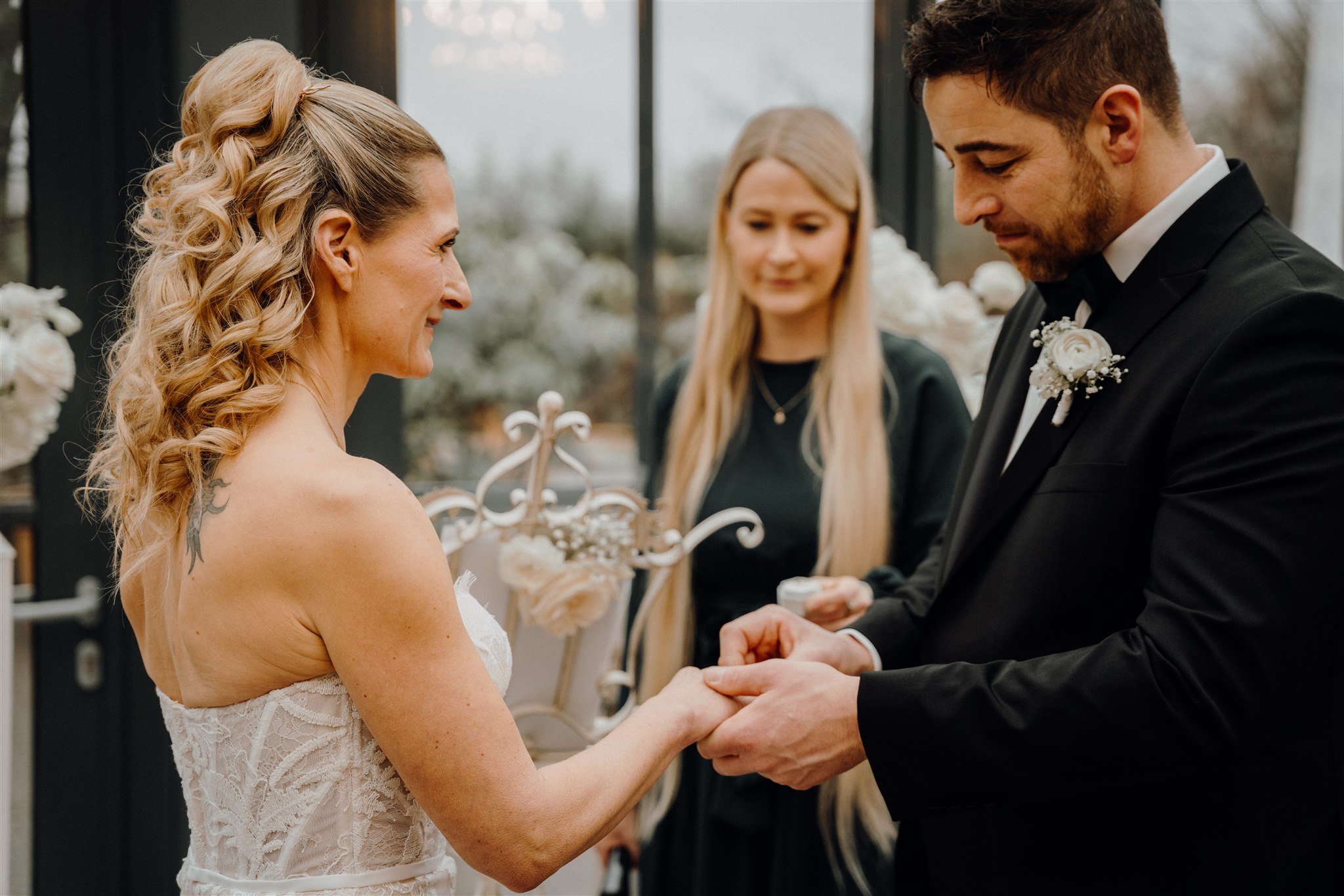 Bräutigam steckt Braut den Ehering an, freie Rednerin steht im Hintergrund, Planung: Sophia von Aspern, von Aspern Weddings, Lüneburg, Hamburg, Hannover, Bremen
