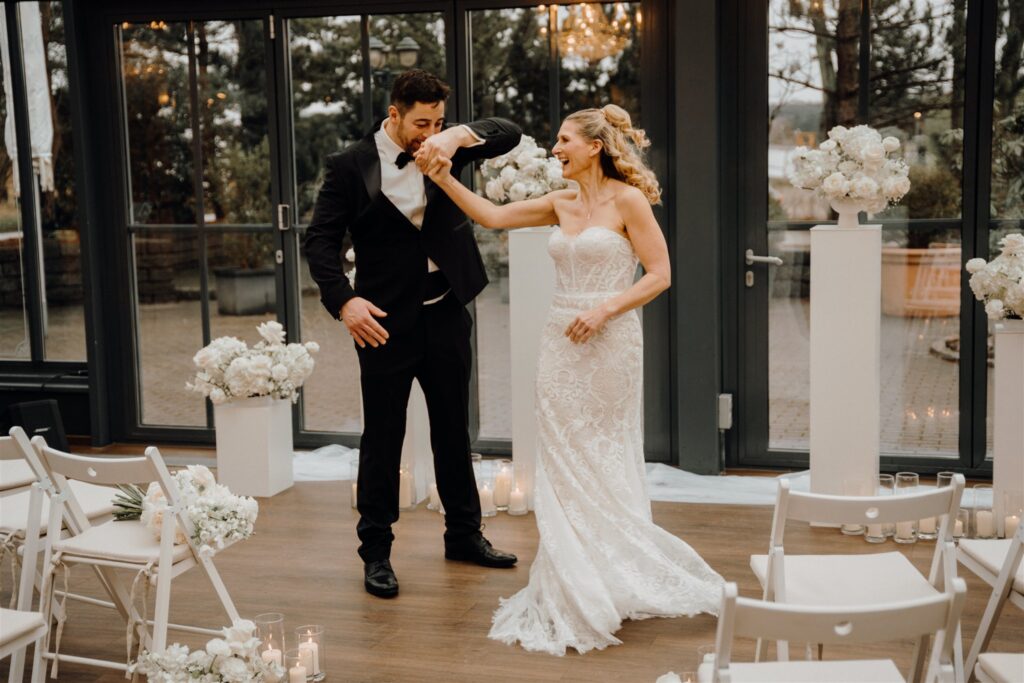 Bräutigam dreht Braut herum vor Trauungssetup inmitten von Blumen und Kerzen, Planung: Sophia von Aspern, von Aspern Weddings, Lüneburg, Hamburg, Hannover, Bremen