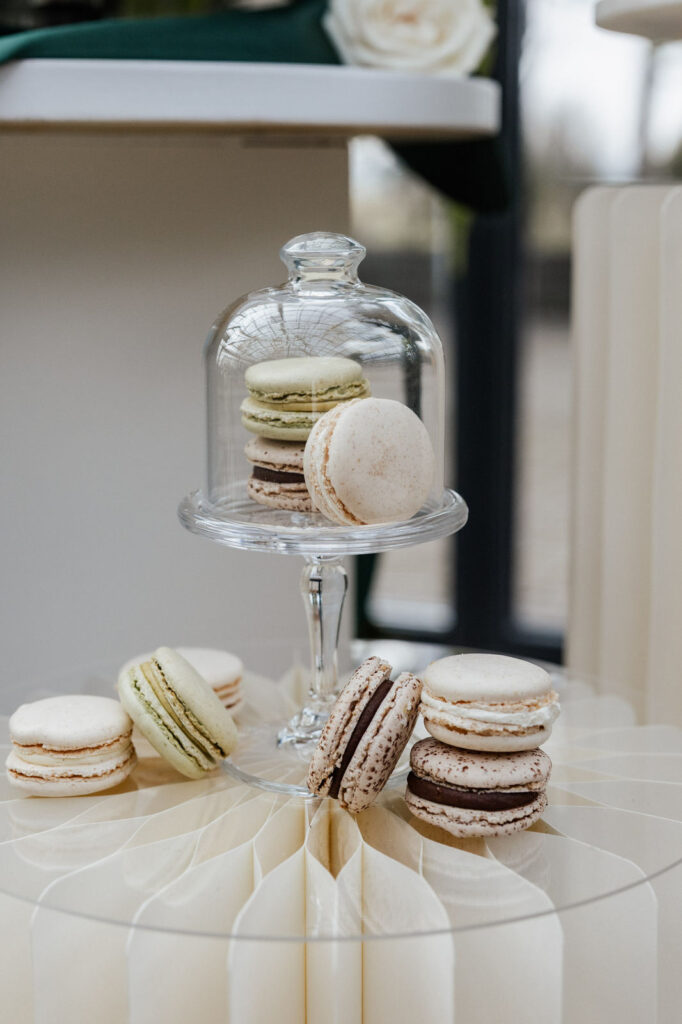 Feine Macarons unter einer eleganten Glashaube – ein liebevolles Detail aus dem Sweet Table, abgestimmt im Rahmen der Hochzeitsplanung mit von Aspern Weddings.