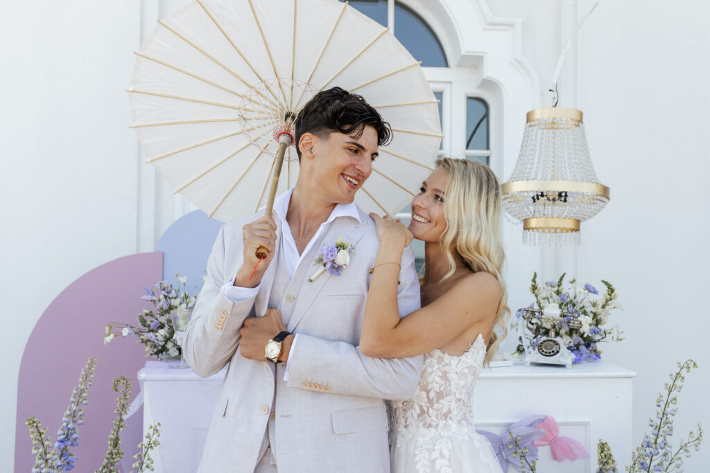 Ein strahlendes Brautpaar steht vor einem kunstvoll dekorierten Tortensetup, festgehalten von Fotografin Sarah Prahm – begleitet durch die Hochzeitsplanung von Sophia von Aspern | von Aspern Weddings | Hamburg, Bremen, Hannover, Niedersachsen.