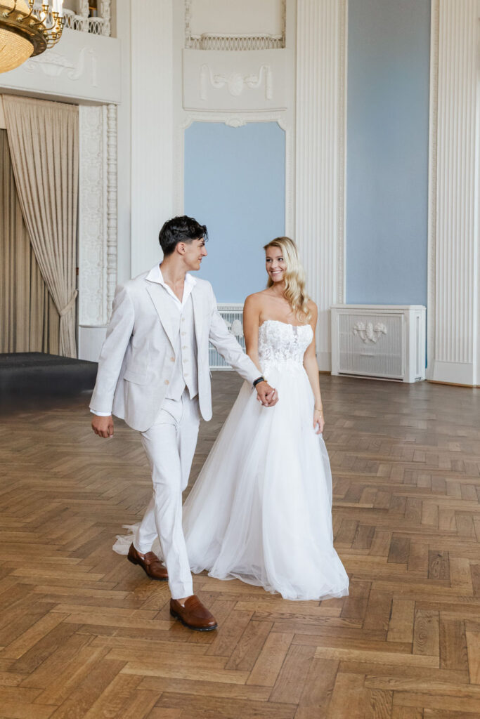 raut und Bräutigam schreiten Hand in Hand durch den festlich dekorierten Ballsaal des Atlantic Hotel Travemünde, begleitet von eleganter Atmosphäre und edlem Lichterglanz – festgehalten von Sophia von Aspern, von Aspern Weddings, Hochzeitsplanung in Hamburg, Hannover, Bremen und Niedersachsen.