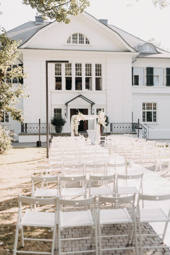 Hochzeitslocation in Hamburg, Villa im Heinepark mit elegantem Trau-Setup im Außenbereich direkt an der Elbe. Stilvolle freie Trauung mit Blick ins Grüne, exklusiv inszeniert durch Hochzeitsplanung von Sophia von Aspern. Heiraten an der Elbe für Paare aus Hamburg, Bremen, Hannover und Niedersachsen, umgesetzt von von Aspern Weddings.