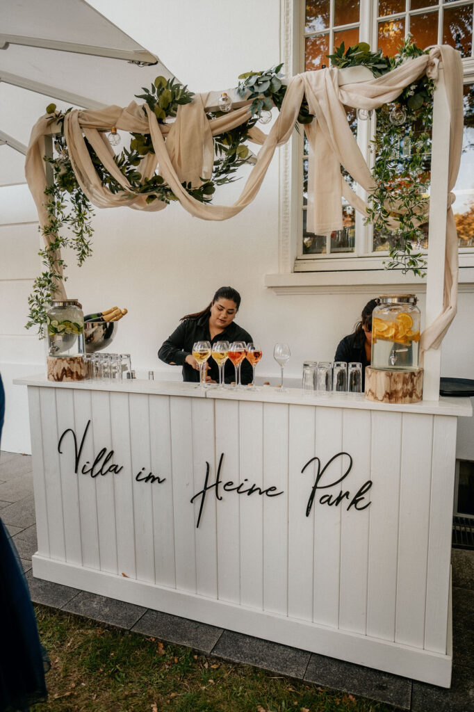 Bartender bereitet Drinks an der stilvollen Bar der Villa im Heine Park in Hamburg zu – fotografiert von Kevin Kurek, Hochzeitsplanung von Aspern Weddings.