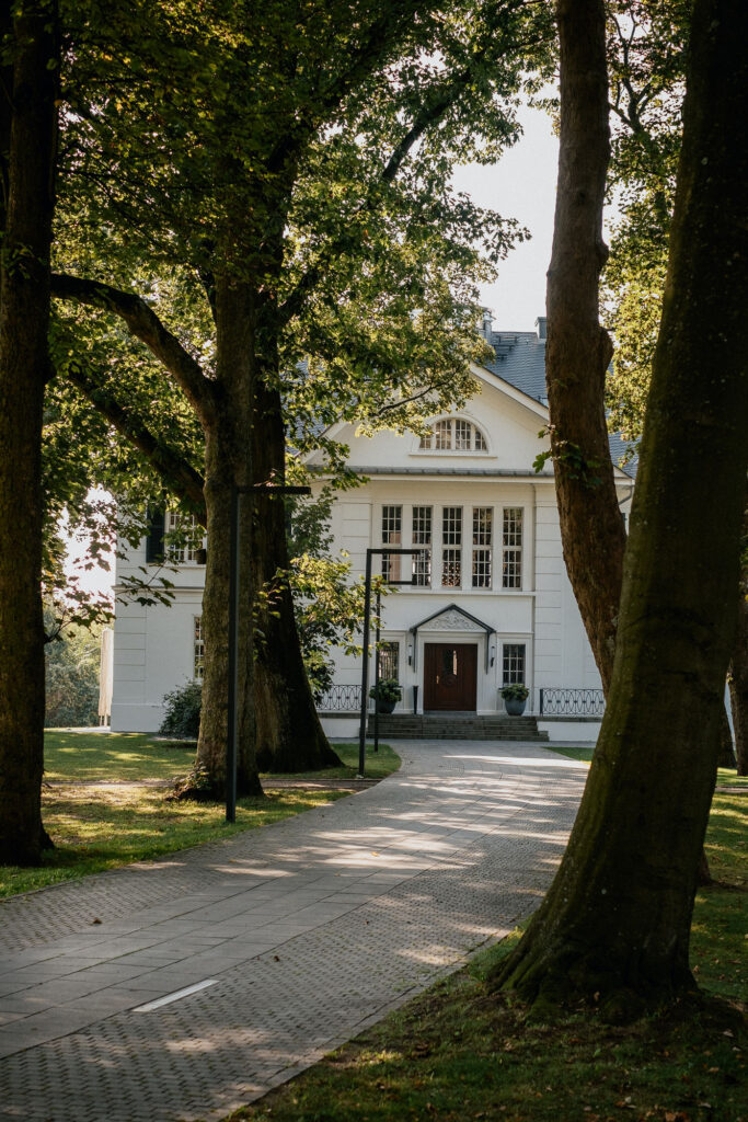 Die Villa im Heine Park in Hamburg im warmen Sonnenlicht, umgeben vom grünen Park – fotografiert von Kevin Kurek, Hochzeitsplanung von Aspern Weddings.