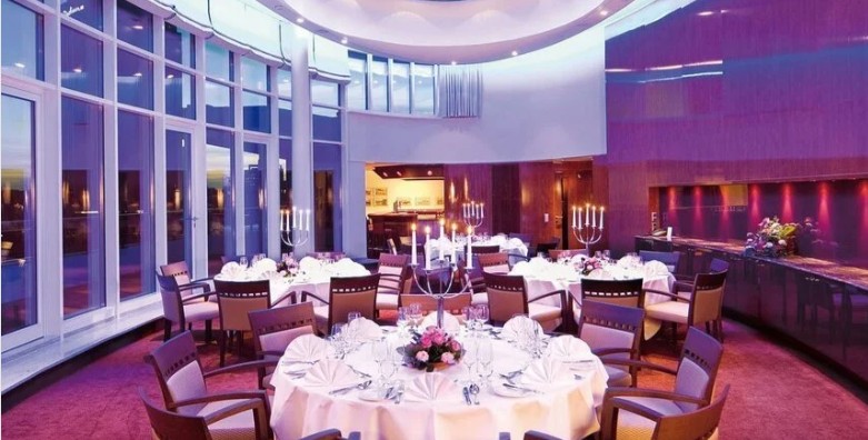 ChatGPT:

Eleganter Festsaal im Grand Elysée Hamburg, geschmückt mit weißen Blumenarrangements, goldenen Akzenten und runden Tischen mit edler Tischdeko. Große Fenster lassen viel Tageslicht herein und verleihen dem Raum eine helle, luxuriöse Atmosphäre – ideal für stilvolle Hochzeitsfeiern mit urbanem Charme. Gäste genießen hier exzellenten Service, feine Küche und das besondere Flair eines exklusiven Grandhotels in zentraler Lage von Hamburg.