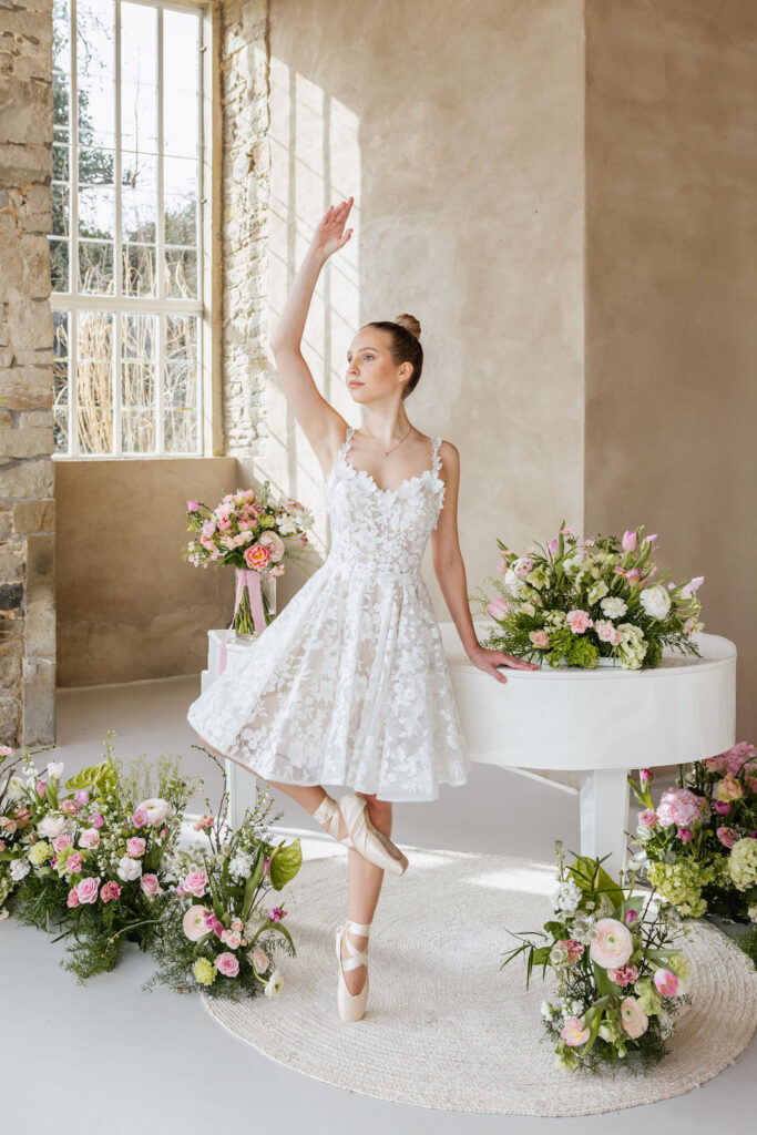 Ballerina tanzt vor einem weißen Piano in der Hochzeitslocation Orangerie Gut Ostenwalde und sorgt für einen besonderen Showmoment während der Feier. Elegante Hochzeitsplanung von Sophia von Aspern für exklusive Hochzeiten in Hamburg, Bremen, Hannover und Niedersachsen.