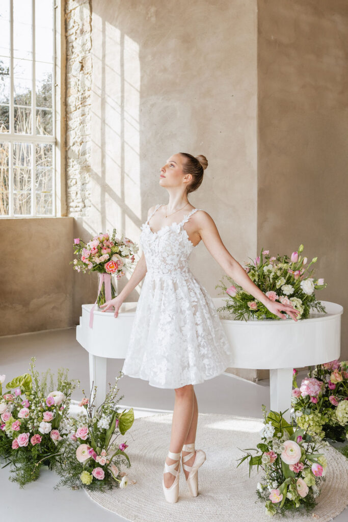 Elegante Ballerina vor weißem Piano in der Hochzeitslocation Orangerie Ostenwalde als besonderes Highlight für exklusive Hochzeitsplanung in Hamburg, Bremen, Hannover und Niedersachsen von Aspern Weddings Sophia von Aspern.