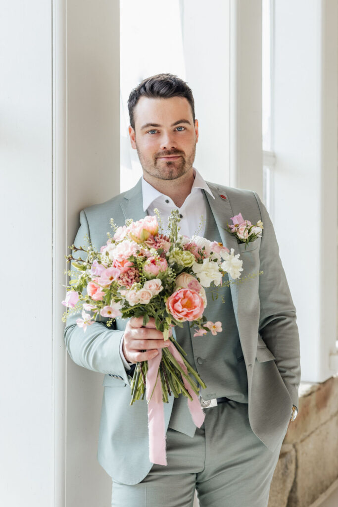 Bräutigam hält den Brautstrauß in der Hand, moderne florale Gestaltung in Lime und Rose mit frischen Grüntönen und zarten Rosénuancen, stilvolle Hochzeitsplanung in Hamburg, Bremen und Hannover, umgesetzt von Sophia von Aspern von Aspern Weddings