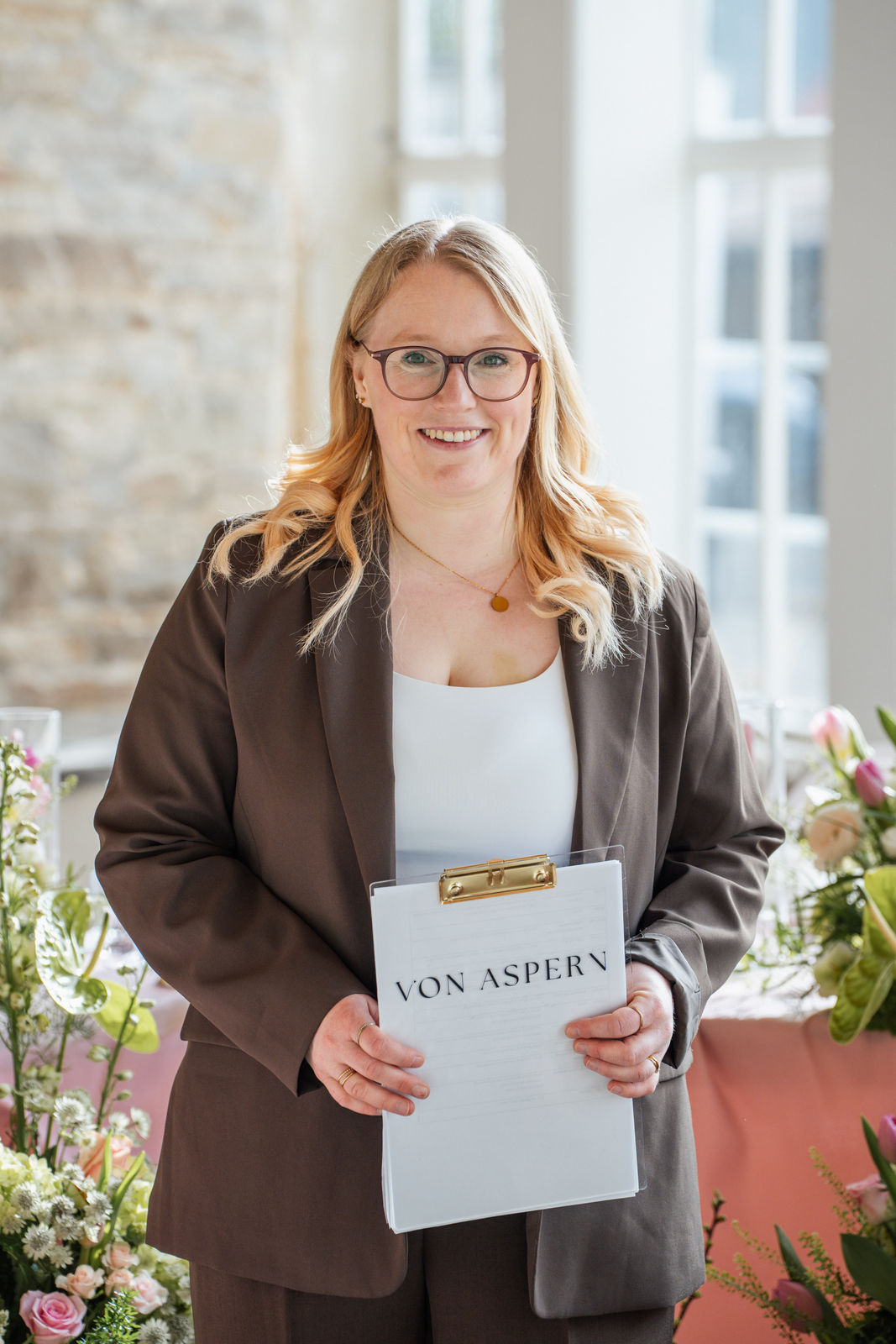Sophia von Aspern steht als Hochzeitsplanerin mit Klemmbrett in der Orangerie Gut Ostenwalde und koordiniert den Ablauf vor Ort mit Blick fürs Detail. Exklusive Hochzeitsplanung von von Aspern Weddings für stilvolle Hochzeiten in Hamburg, Bremen, Hannover und Niedersachsen.