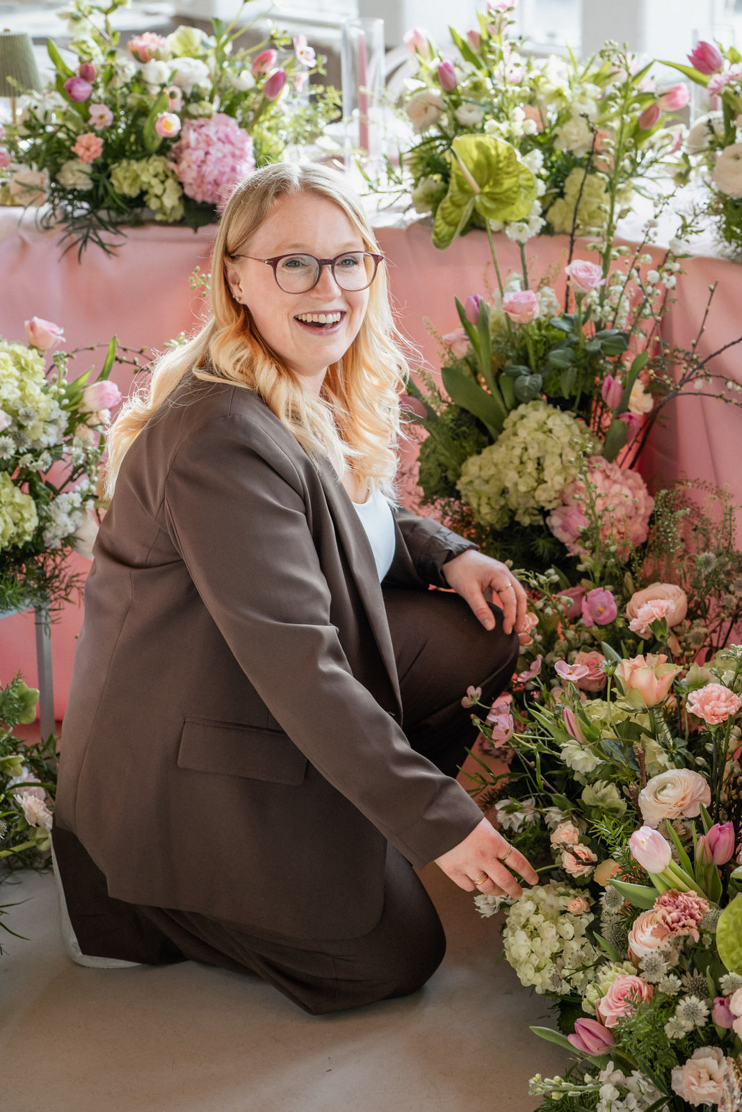 Sophia von Aspern richtet die Blumendekoration für eine Hochzeit und platziert letzte Details im floralen Setup. Die Szene zeigt exklusive Hochzeitsplanung von von Aspern Weddings für stilvolle Hochzeiten in Hamburg, Bremen, Hannover und Niedersachsen.