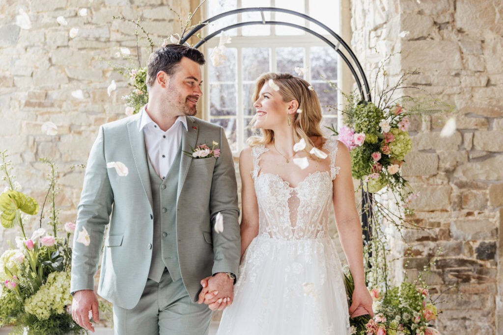 Brautpaar beim emotionalen Auszug in der Orangerie von Gut Ostenwalde während Gäste Blüten werfen. Elegante Hochzeitsplanung in Niedersachsen mit exklusiver Atmosphäre und besonderen Momenten für Hochzeiten in Hamburg, Bremen und Hannover. Sophia von Aspern von Aspern Weddings begleitet hochwertige Hochzeiten mit viel Liebe zum Detail.