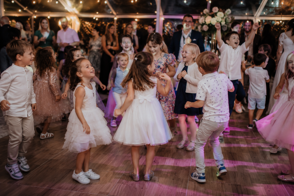 Mehrere Kinder tanzen gemeinsam auf der Tanzfläche einer Hochzeit und haben sichtbar Spaß während der Feier. Kinder können bei einer Hochzeit für besondere Momente sorgen, wenn die Hochzeitsplanung in Hamburg, Bremen, Hannover und Niedersachsen passende Angebote für Familien berücksichtigt.