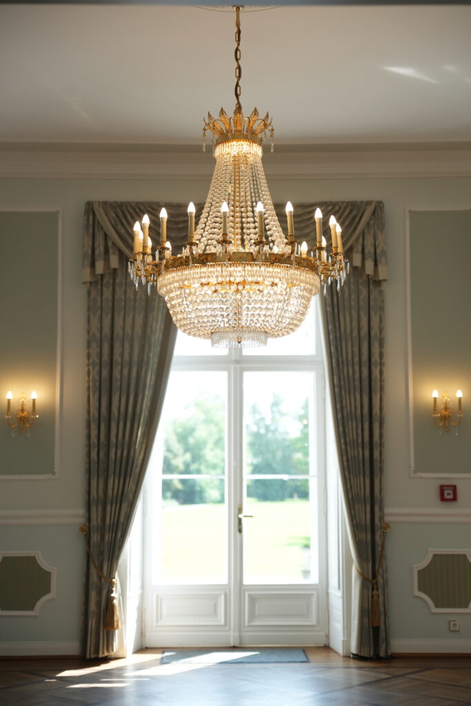 Eleganter Kronleuchter im Trauraum von Schloss Ovelgönne, in dem freie Trauungen in stilvoller Atmosphäre stattfinden können. Begleitet durch Sophia von Aspern von von Aspern Weddings im Rahmen einer exklusiven Hochzeitsplanung in Niedersachsen, Hamburg, Bremen und Hannover.