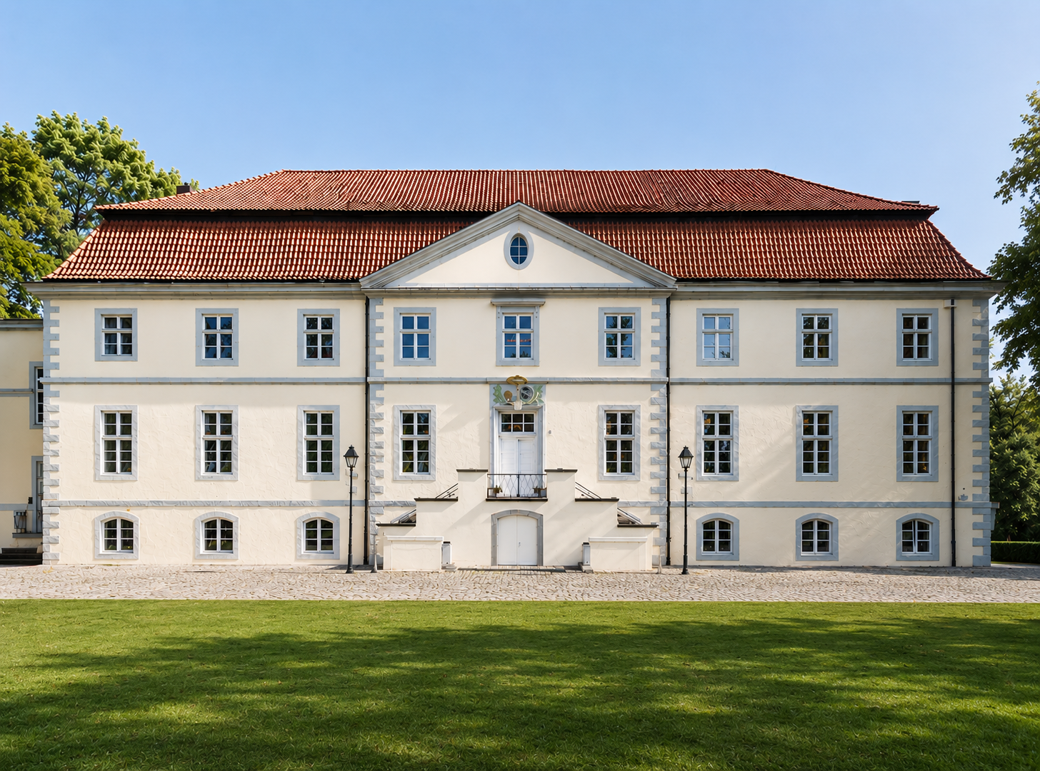 Außenansicht von Schloss Ovelgönne mit Blick auf die gepflegte Rasenfläche und die historische Hochzeitslocation. Schloss Ovelgönne ist eine stilvolle Location für exklusive Hochzeiten und Hochzeitsplanung in Hamburg, Bremen, Hannover und Niedersachsen.