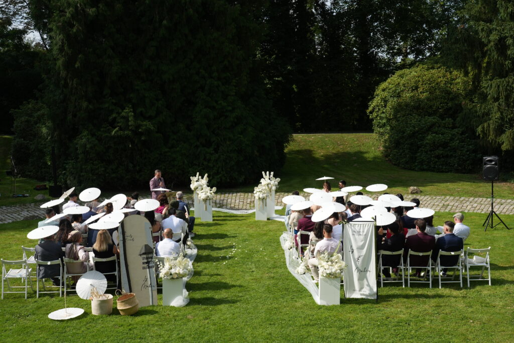 Trauungssetup im Schloss Ovelgönne mit Brautpaar und Gästen, fotografiert mit Blick auf die umliegende Landschaft und den Ausblick der Hochzeitslocation. Hochzeitsplanung in Niedersachsen, Hamburg, Bremen und Hannover.