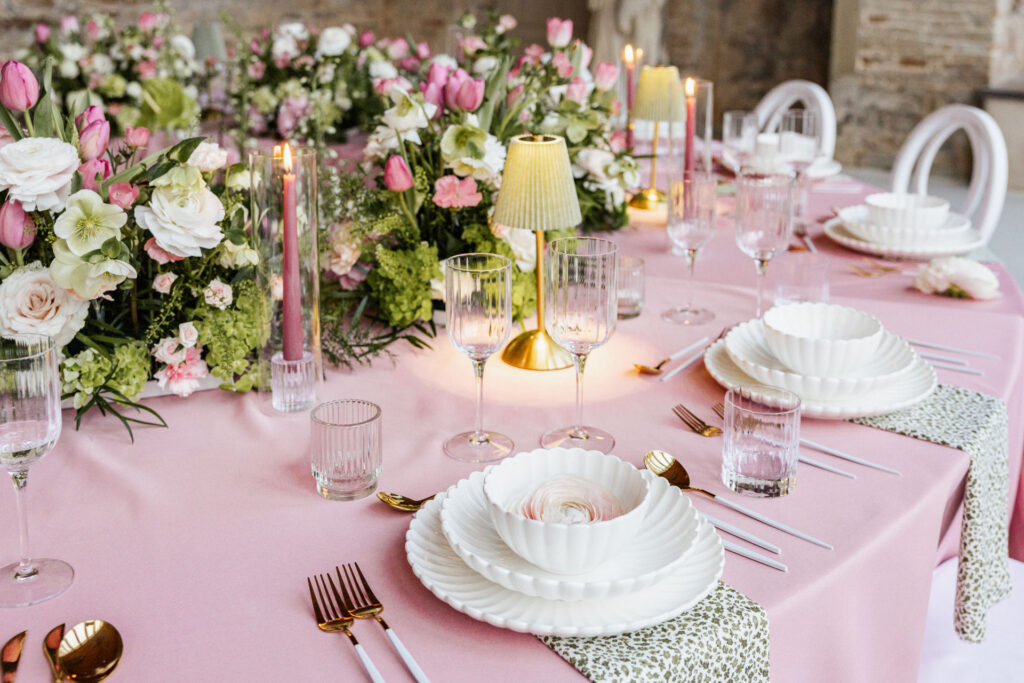 Stilvolles Tischsetting mit rosaner Tischdecke, floralen Elementen und dekorativen Lampen als moderner Hochzeitstrend. Hochwertige Hochzeitsinspiration aus einem geplanten Shooting für exklusive Hochzeiten in Hamburg, Bremen, Hannover und Niedersachsen mit Sophia von Aspern von Aspern Weddings.