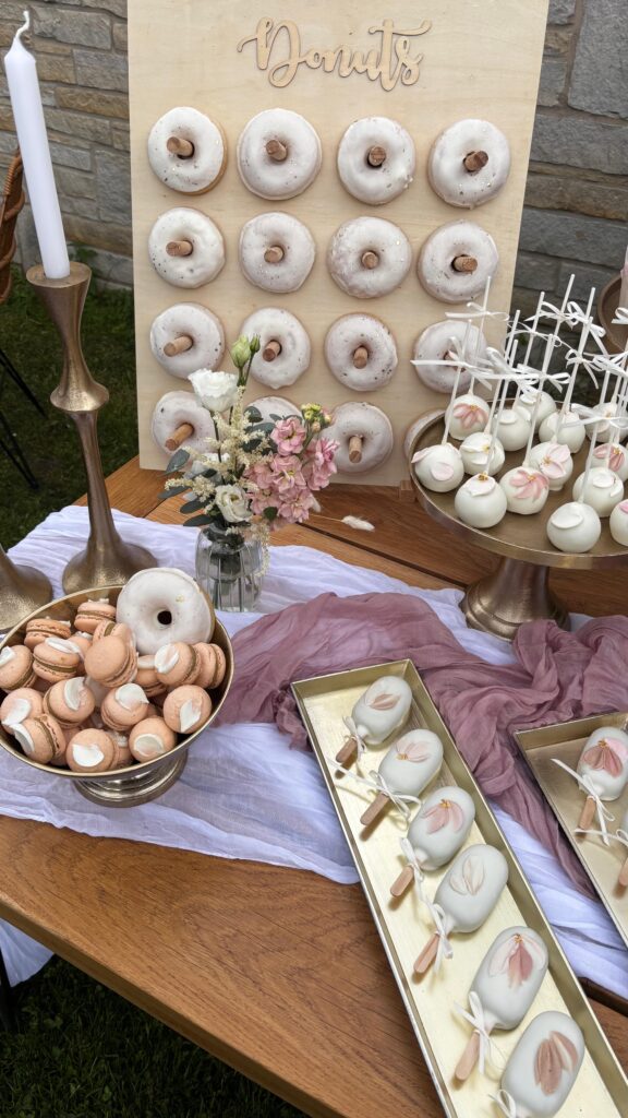 Liebevoll gestalteter Sweet Table im Rittergut Remmeringhausen mit moderner zweistöckiger Hochzeitstorte, Dessertgläsern, Donuts, Cupcakes, Macarons, Cakecicles und Cakepops. Harmonisches Farbkonzept und stilvolle Dessertpräsentation von Sanelas Tortenwelt, begleitet durch exklusive Hochzeitsplanung von Aspern Weddings in Hamburg, Bremen, Hannover und Niedersachsen.