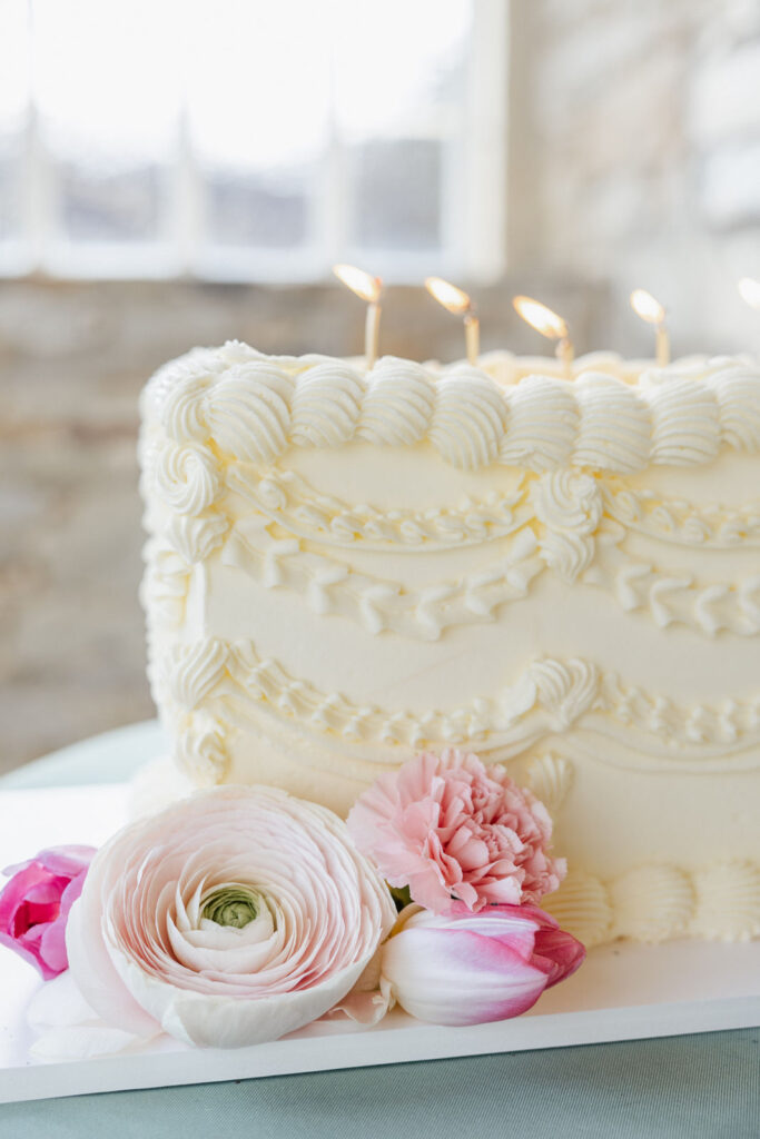 Detailaufnahme einer modernen rechteckigen Hochzeitstorte mit floralen Elementen in der Orangerie Gut Ostenwalde. Hochwertiges Tortendesign für elegante Hochzeiten und exklusive Hochzeitsplanung mit von Aspern Weddings in Hamburg, Bremen, Hannover und Niedersachsen.